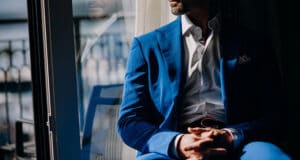 thoughtful-man-blue-suit-sits-windowsill